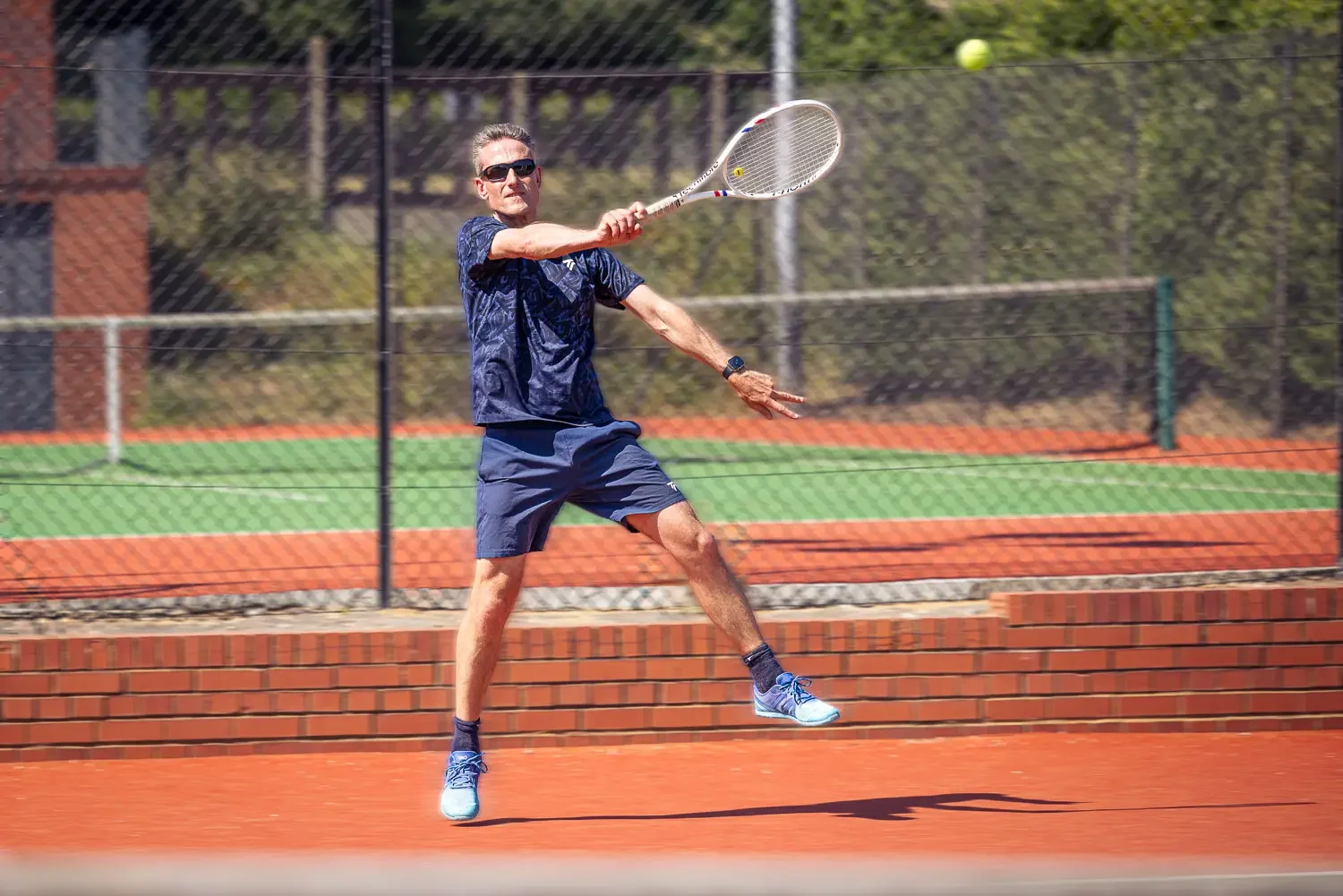 Tennis coach Howard hitting a forehand on the clay court at Greenwood Park Lawn Tennis Club, St Albans