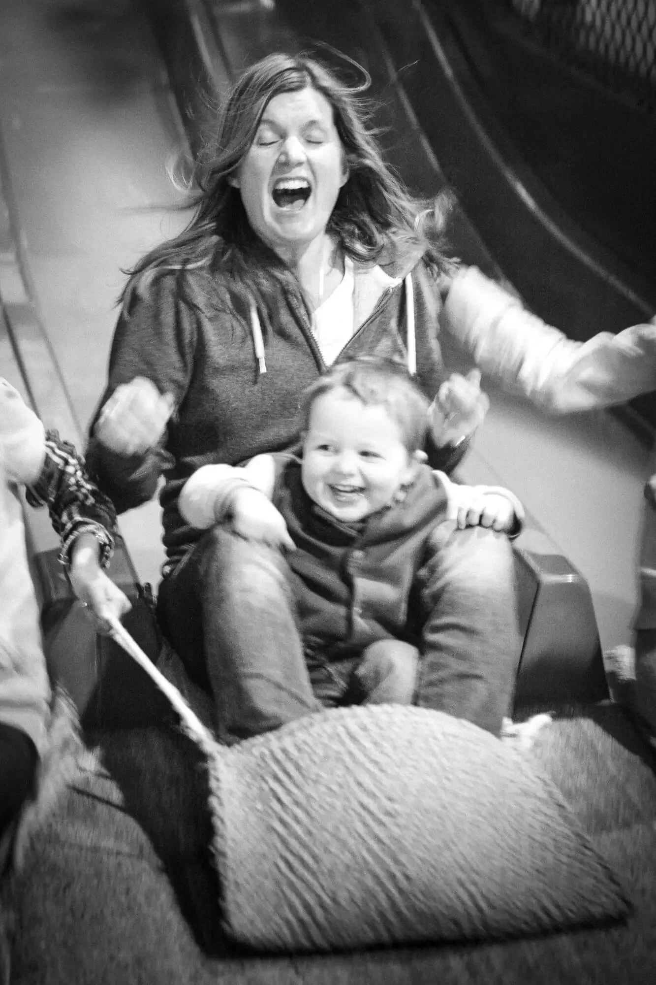A woman and a young boy on a roller coaster ride, both smiling and expressing excitement.