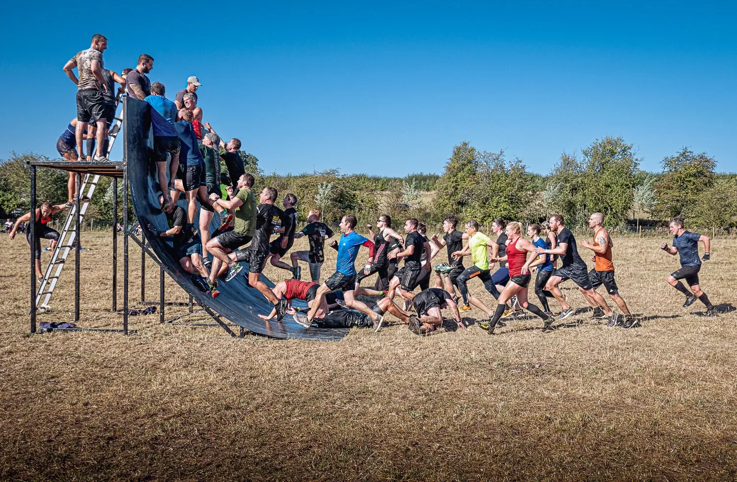 Composite photograph of obstacle race wall climb showing multiple competitors simultaneously, created in Photoshop from individual source images