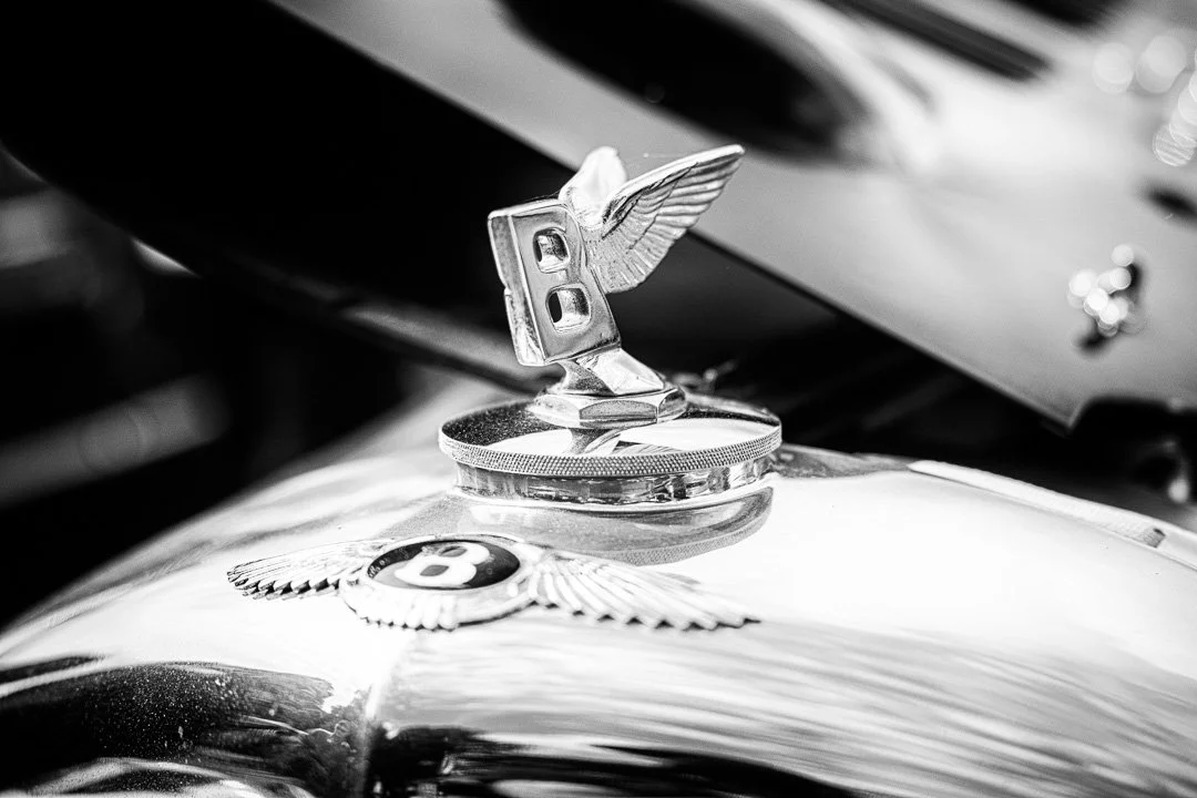 A close up of a flying B with wings on a classis Bentley car.jpg