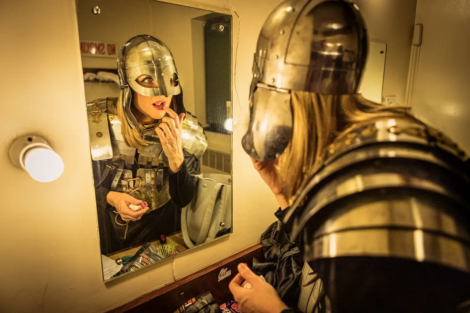 Panto-character-dressed-in-a-armour-applies-makeup-in-dressing-room.webp