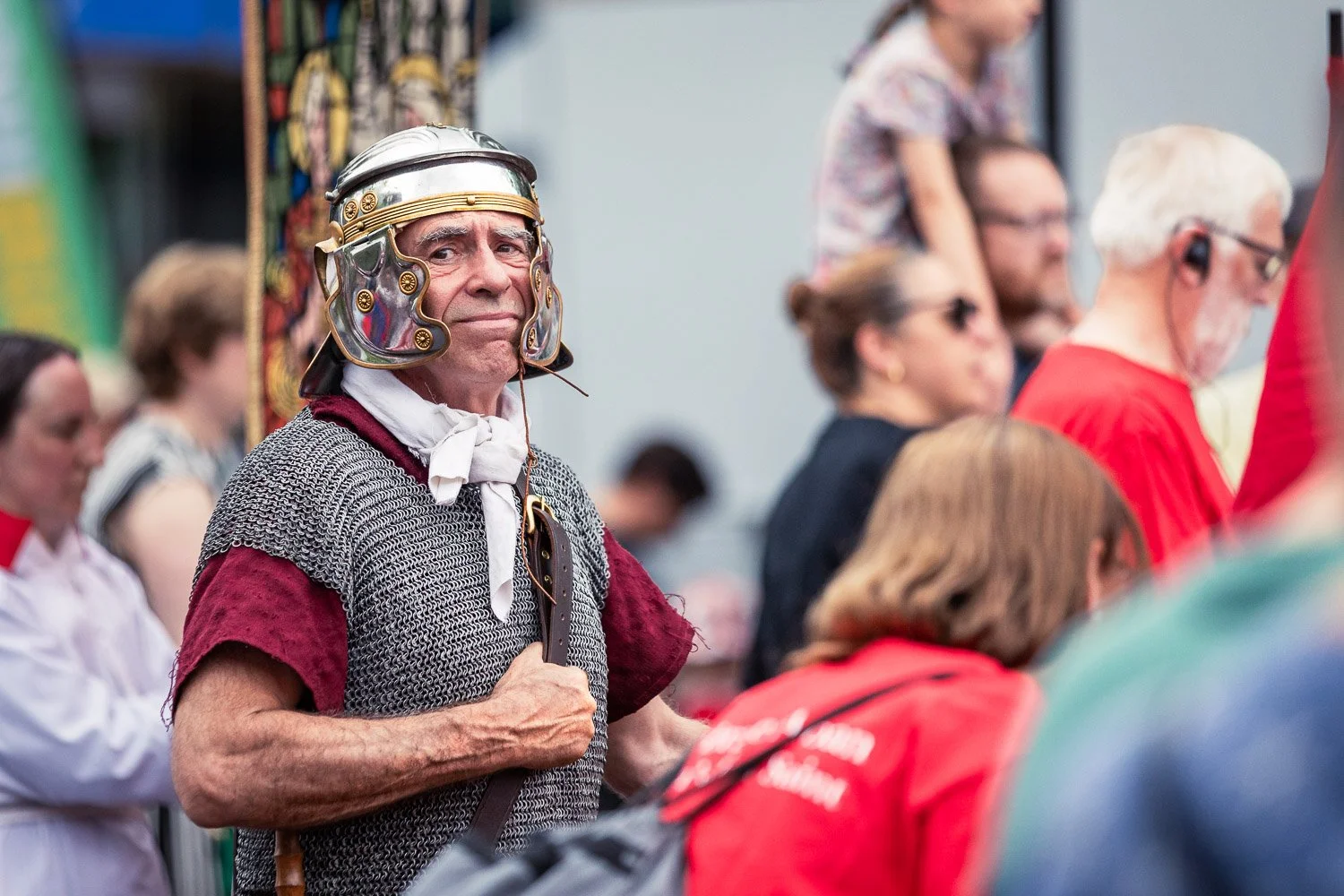  Roman soldier reenactor in chainmail and polished helmet watching the Alban Day 2026 procession in St Albans, Hertfordshire, surrounded by a crowd of spectators 