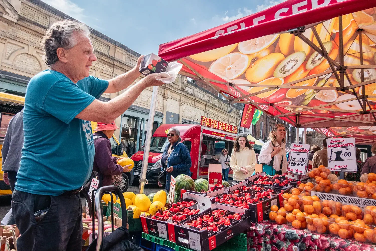 Fruit and veg stallholder serving customers at St Albans market