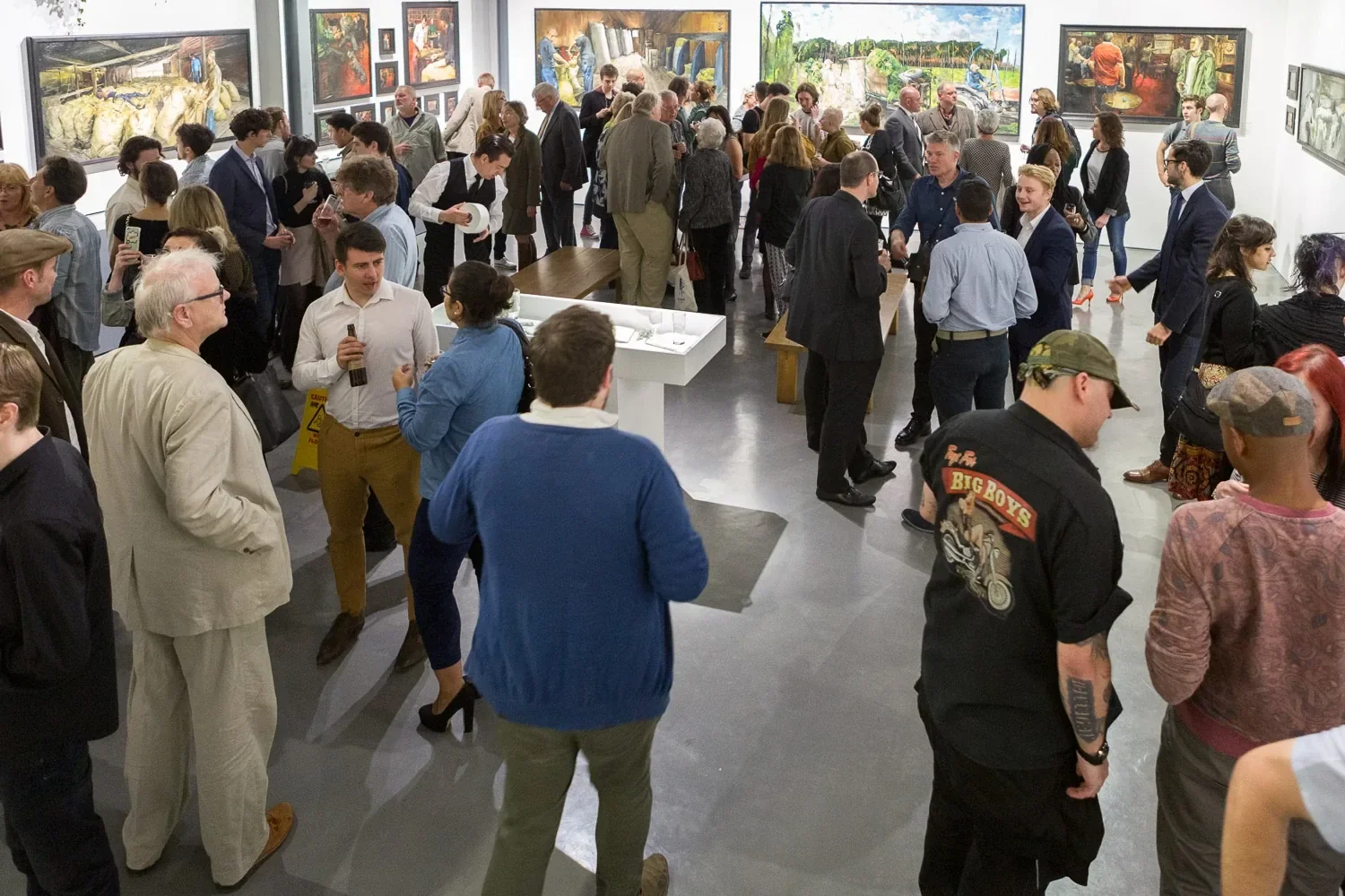 Crowd at a gallery private view surrounded by large paintings, London