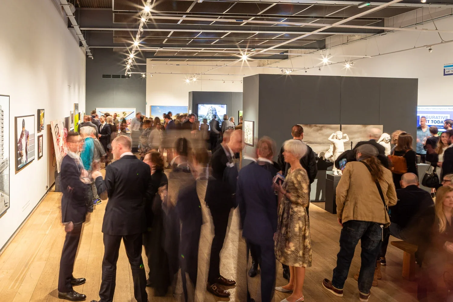 Guests at an art prize private view in a London gallery, with motion blur showing the busy room