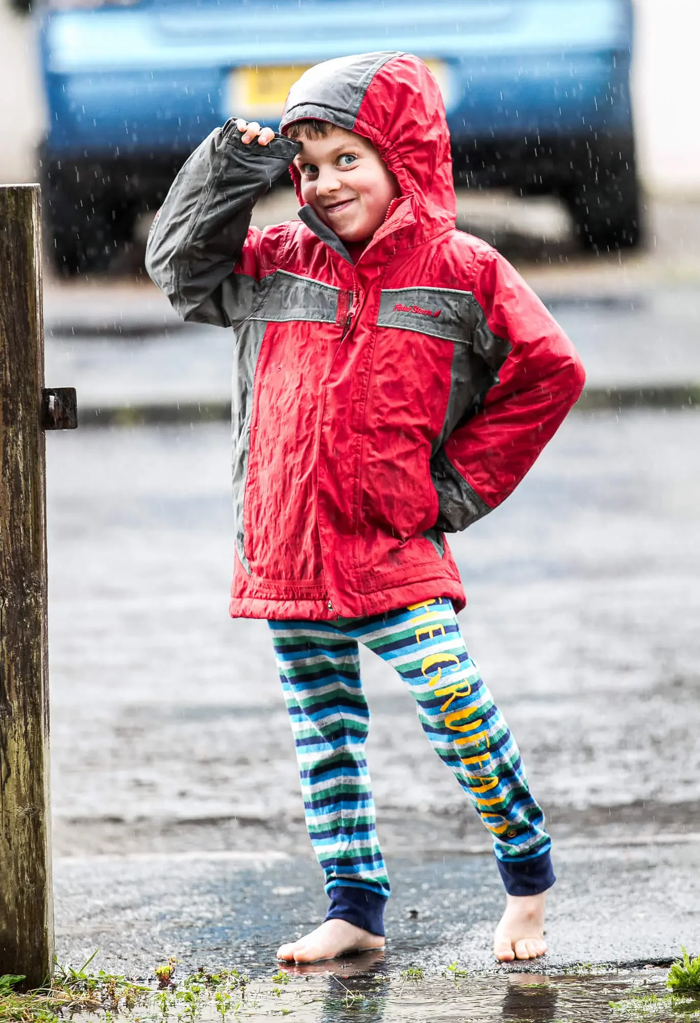 A small boy wearing a rain jacket having fun in the rain.