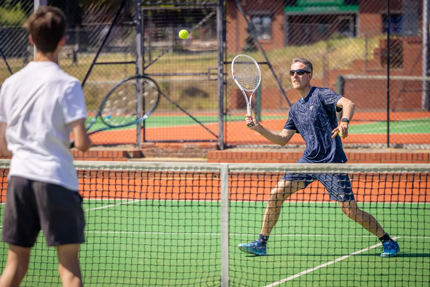 Tennis coach Howard hitting a forehand during a coaching session on the astro court at Greenwood Park Lawn Tennis Club, St Albans