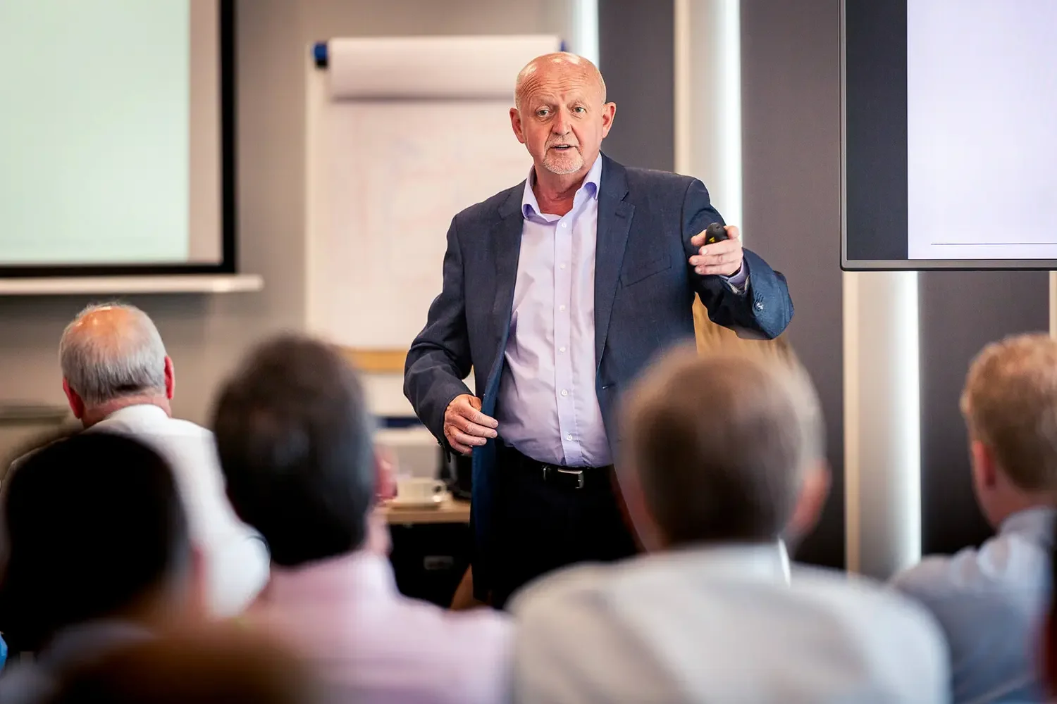 A male presenter talking to a corporate audience in an office environment.