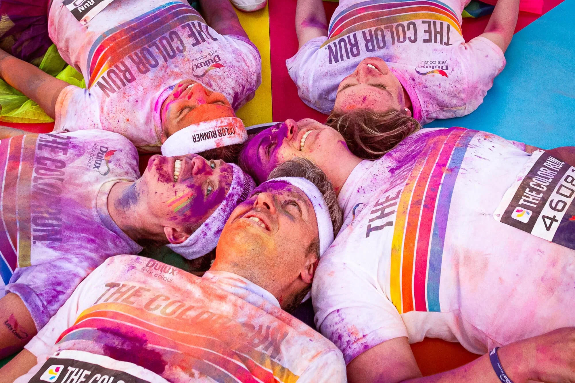 Group of colour run participants lying together covered in coloured powder