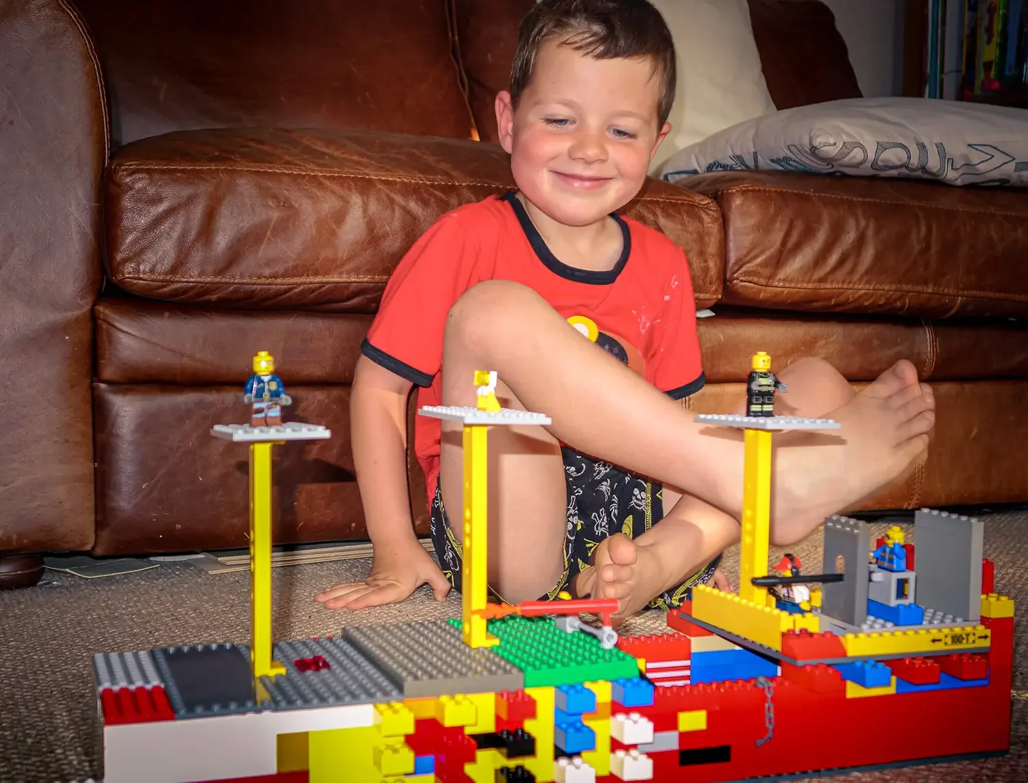 A young boy sitting down playing with lego.
