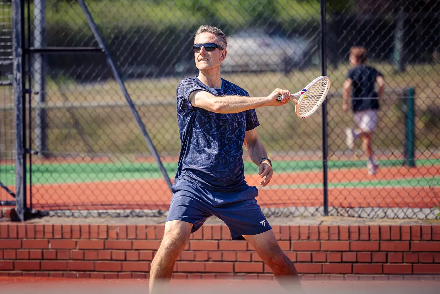 Tennis coach Howard playing a backhand shot on the clay court at Greenwood Park Lawn Tennis Club, St Albans