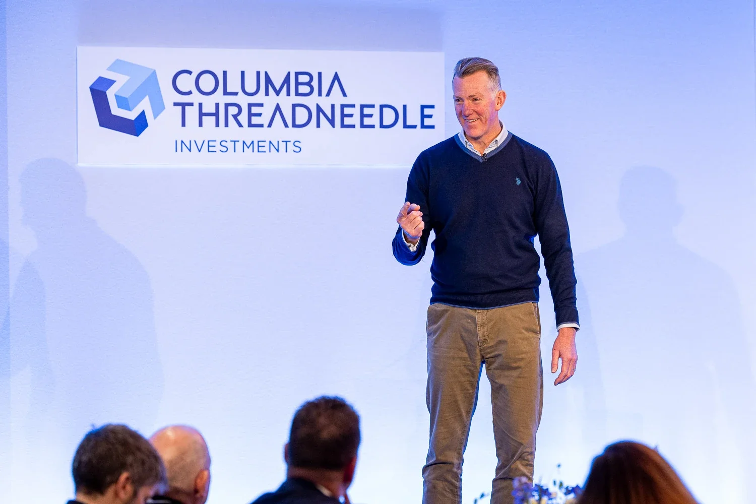 Keynote speaker on stage at a corporate conference in London, with space around him for cropping