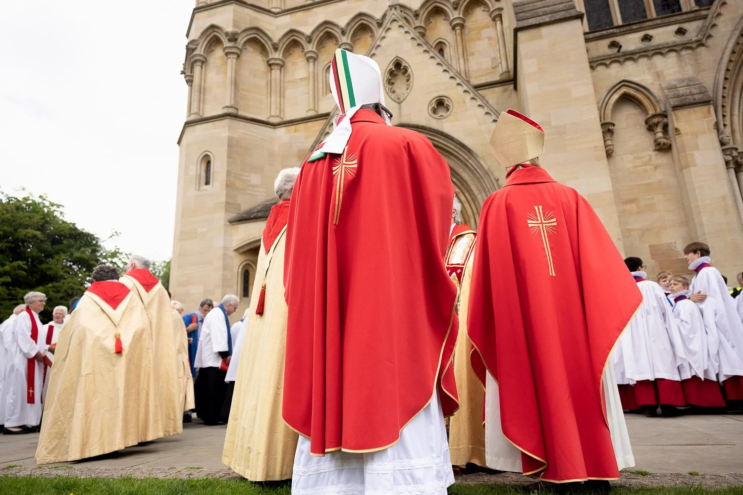 Clergy in red and gold vestments processing towards the west front of St Albans Cathedral during Alban Day 2026, Hertfordshire.