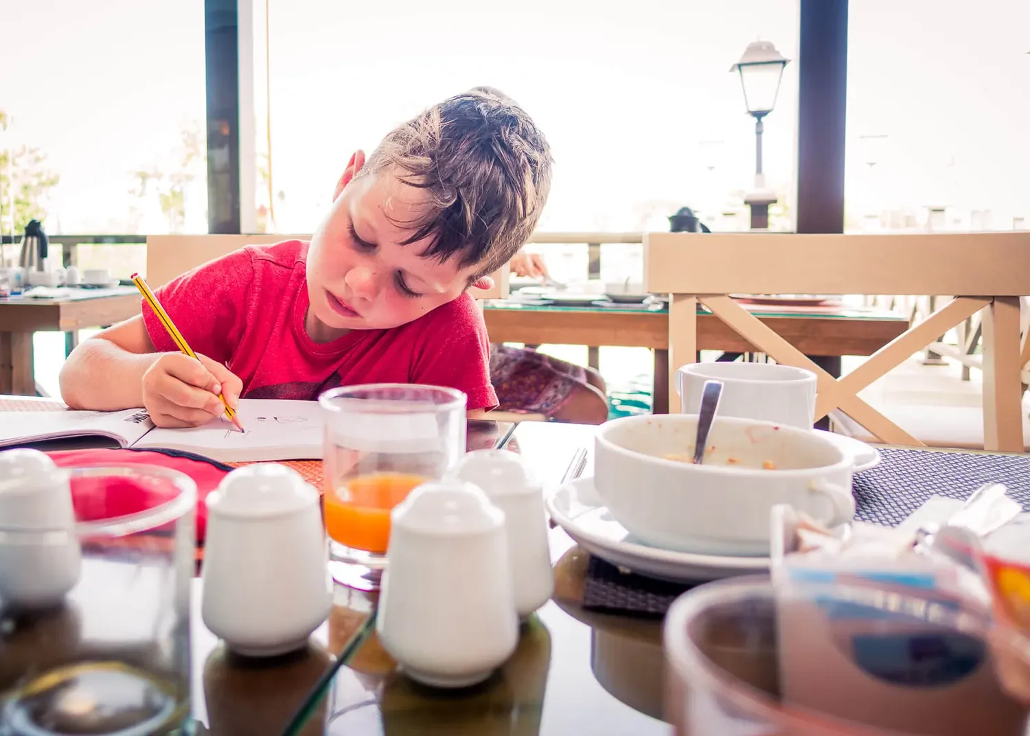 Young boy sketching in a notebook at the breakfast table during a family photography session in St Albans