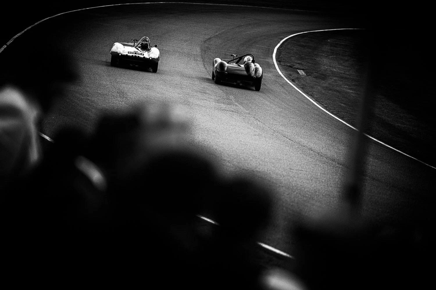 Two classic race cars cornering at Goodwood Revival, black and white