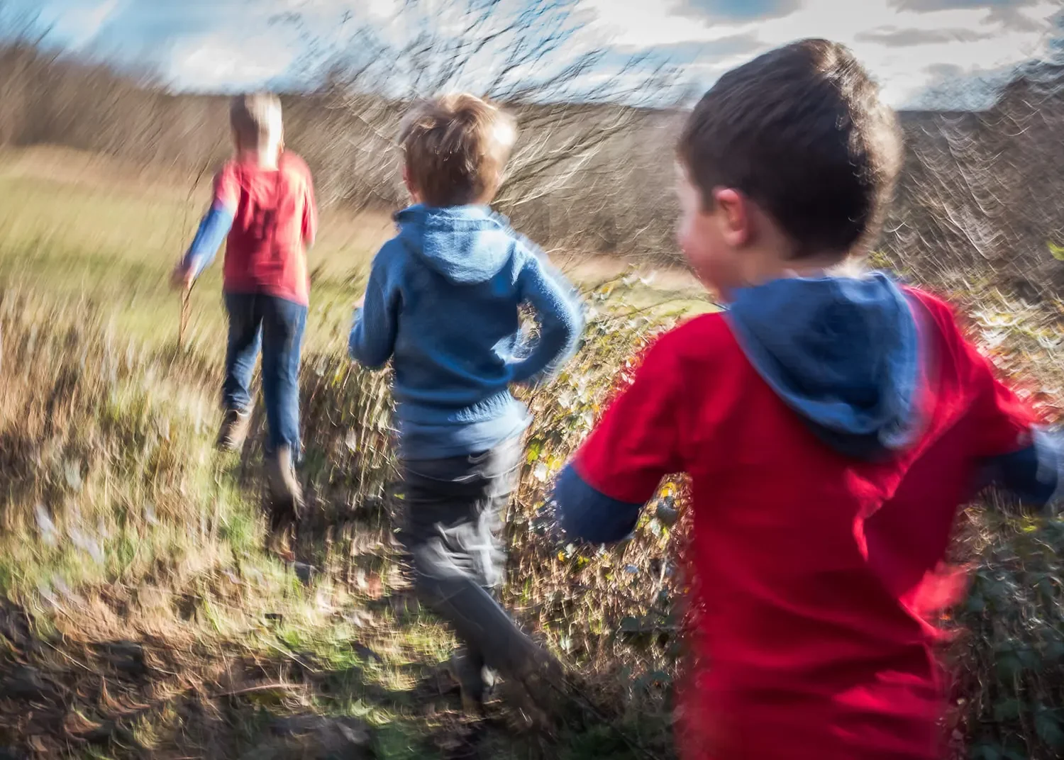 Three children running along a trail in Hertfordshire during an outdoor family photography session near St Albans