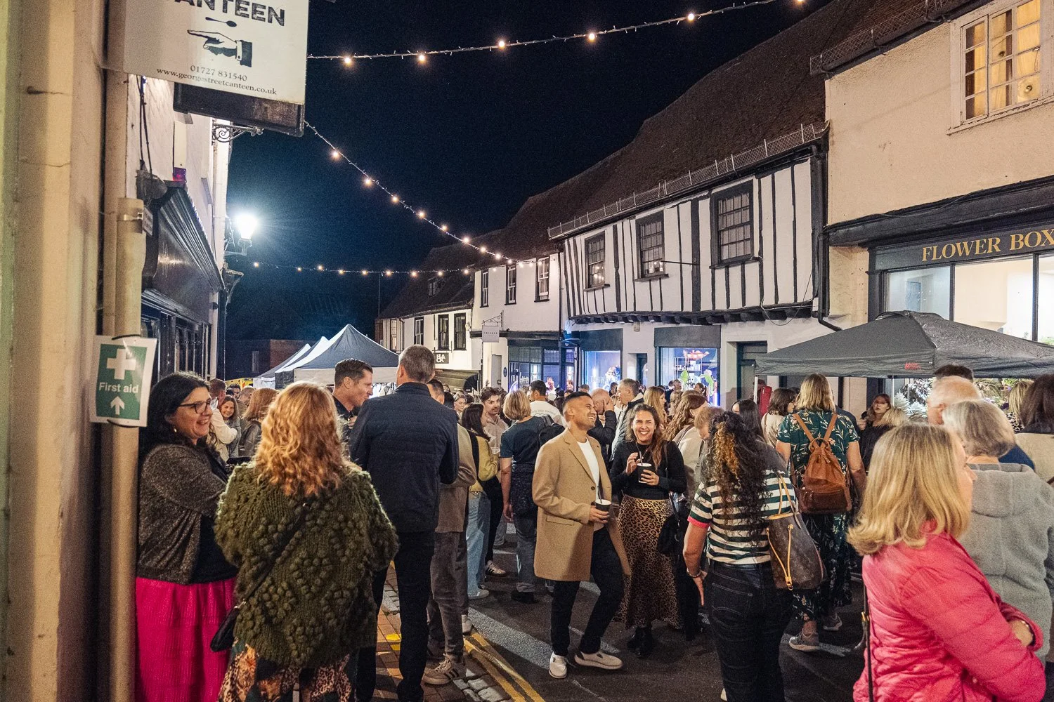Busy George Street outside George Street Canteen, St Albans, at night with festoon lights between the buildings