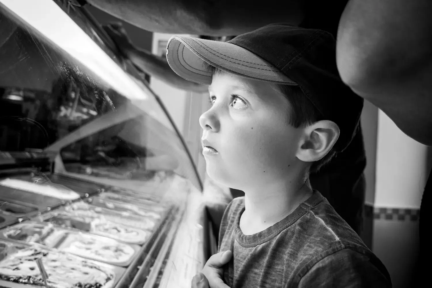 A young boy looking longfully at ice cream.