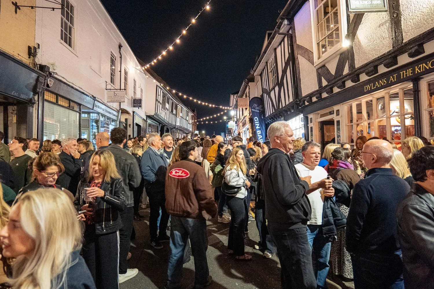 Crowds packing George Street, St Albans, at night under strings of festoon lights