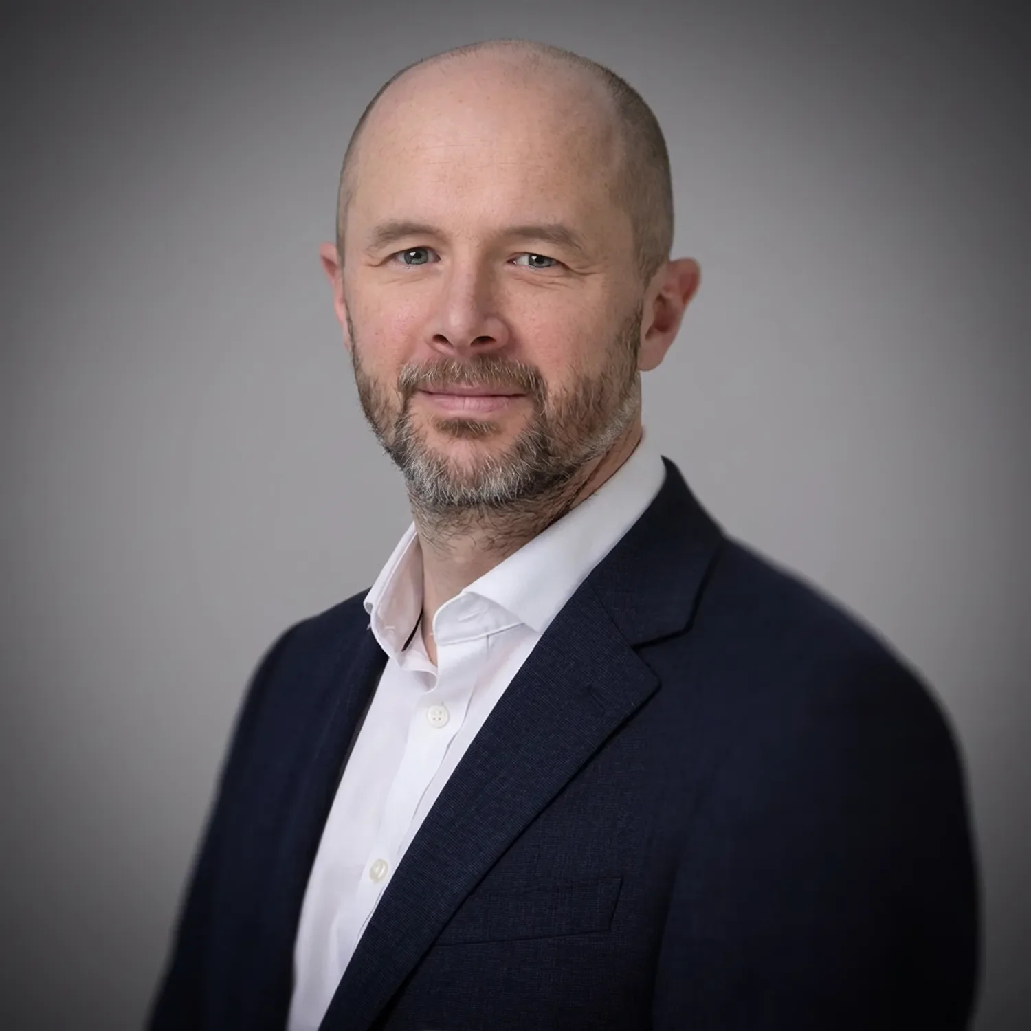 A corporate portrait of a businessman wearing a dark blue jacket and white shirt