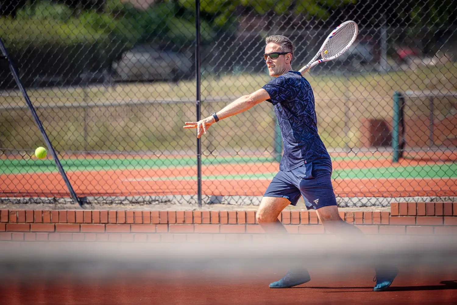 Tennis coach Howard striking a forehand on the clay court at Greenwood Park Lawn Tennis Club, St Albans