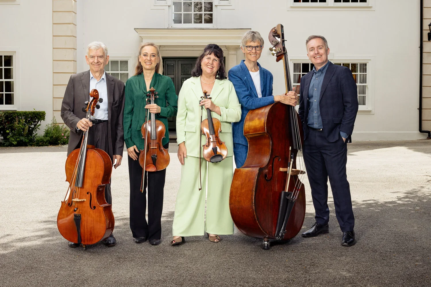 Five classical musicians standing in open shade on a driveway in Arkley, Barnet, lit with off-camera flash for an outdoor group publicity photo.