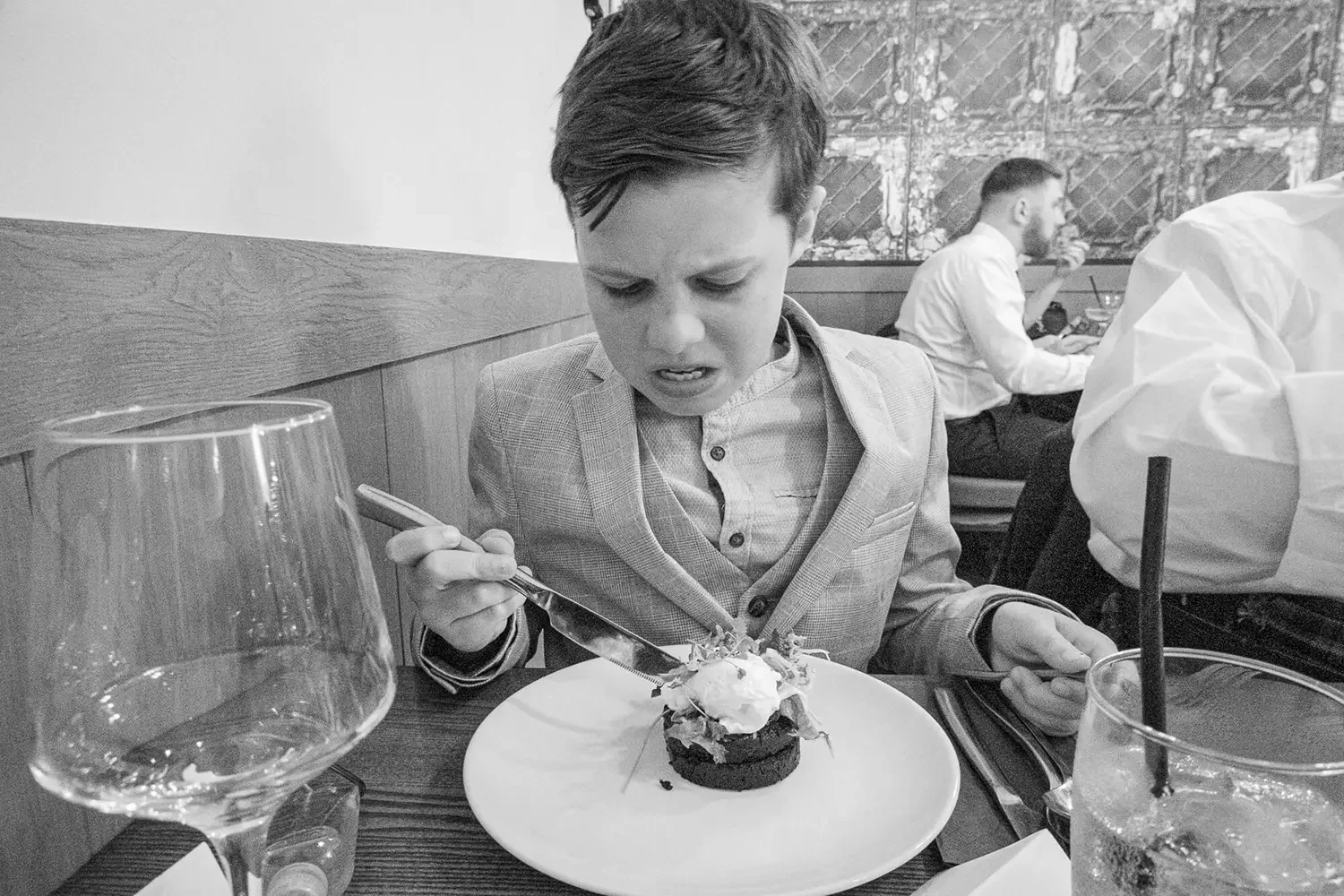 Young boy in restaurant does not look like he's enjoying his food.
