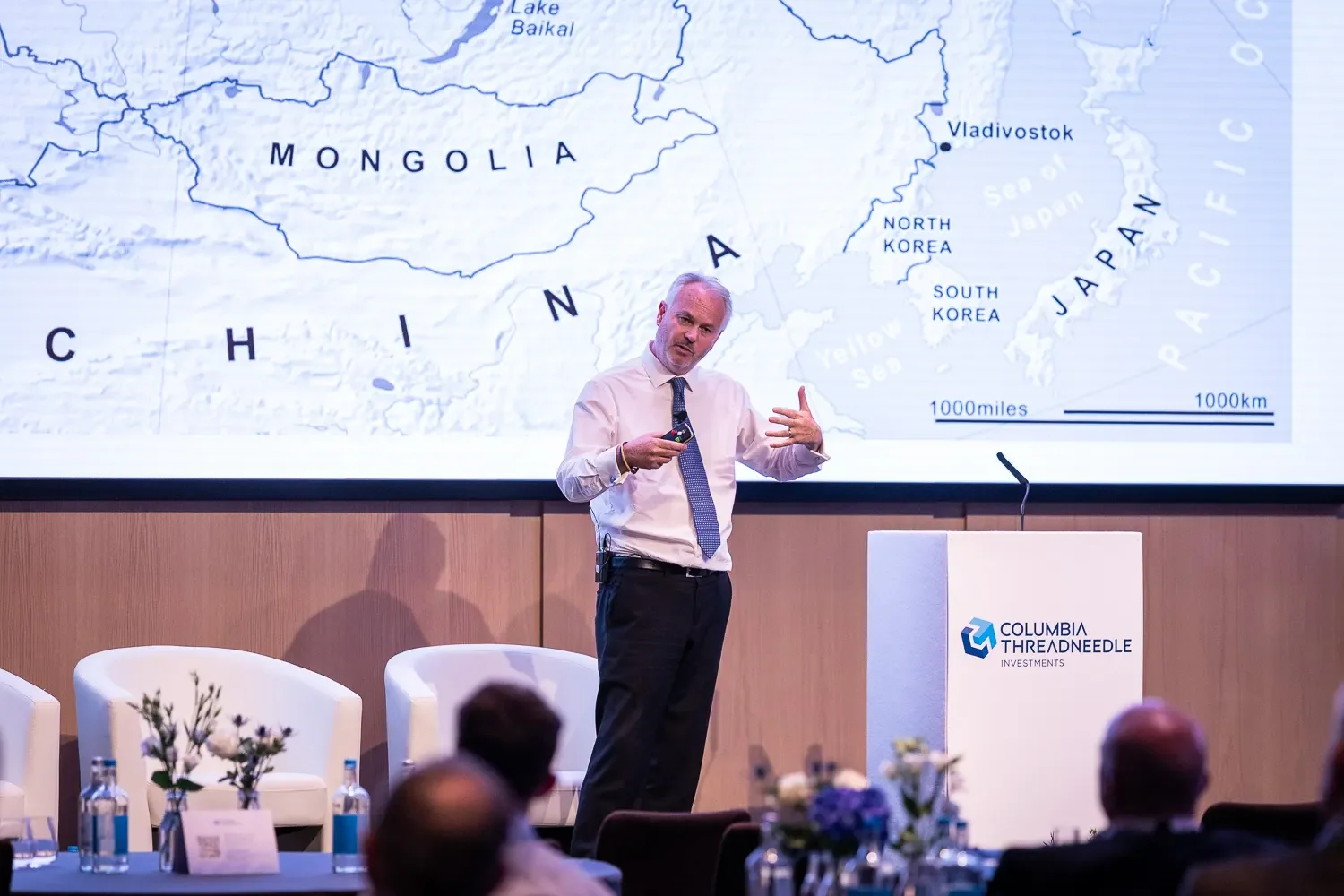 Conference speaker presenting with a map slide at a Columbia Threadneedle Investments event in London.