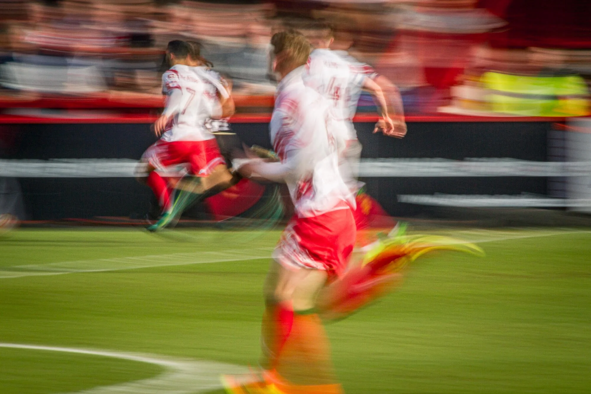 layers sprinting onto the pitch, shot with a slower shutter to convey speed and energy.
