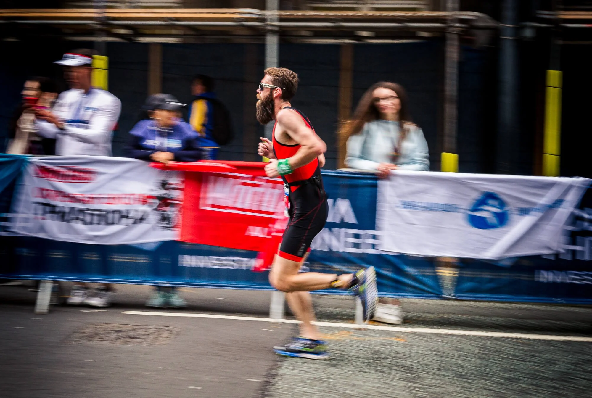 Bearded triathlete running the final leg past supporters