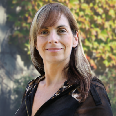 Woman smiling outdoors with foliage background