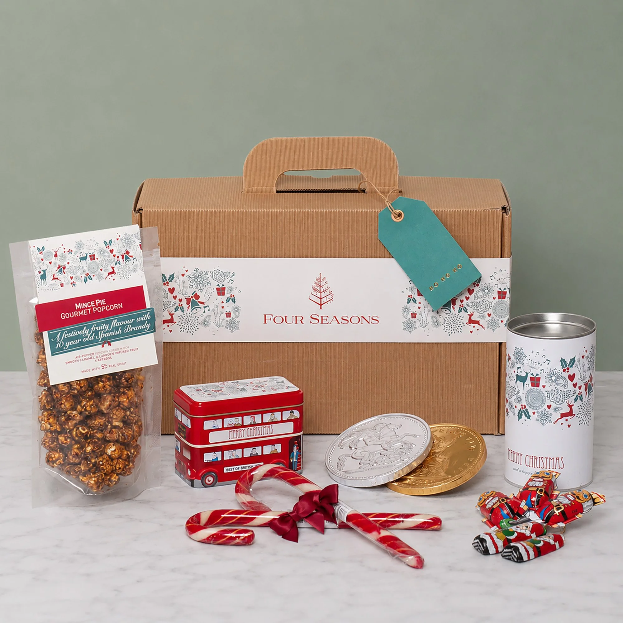 Branded Corporate Christmas Hampers for Four Seasons Hotels containing Mince Pie Popcorn, Candy Canes, Chocolate Coins, Tree Directions in Suitcase Style Hamper Box