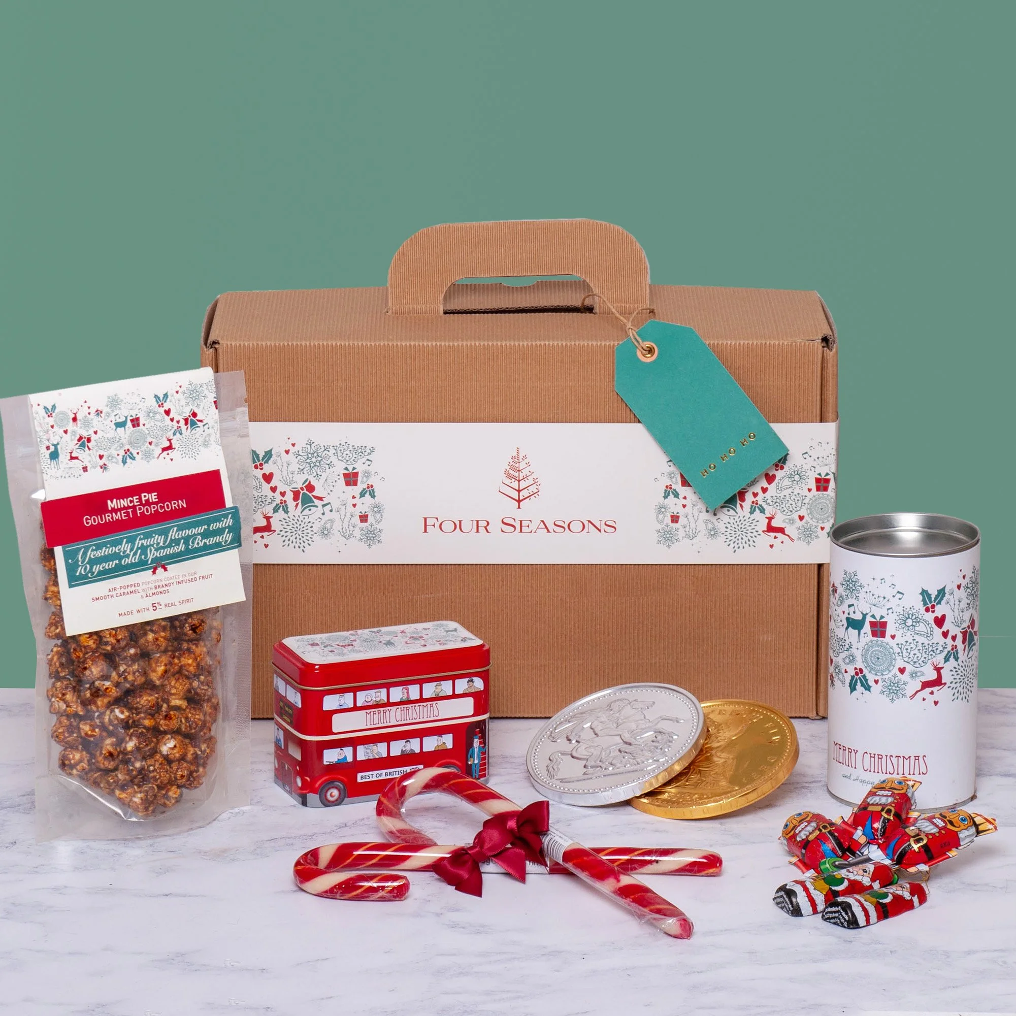 Branded Corporate Christmas Hampers for Four Seasons Hotels containing Mince Pie Popcorn, Candy Canes, Chocolate Coins, Tree Directions in Suitcase Style Hamper Box