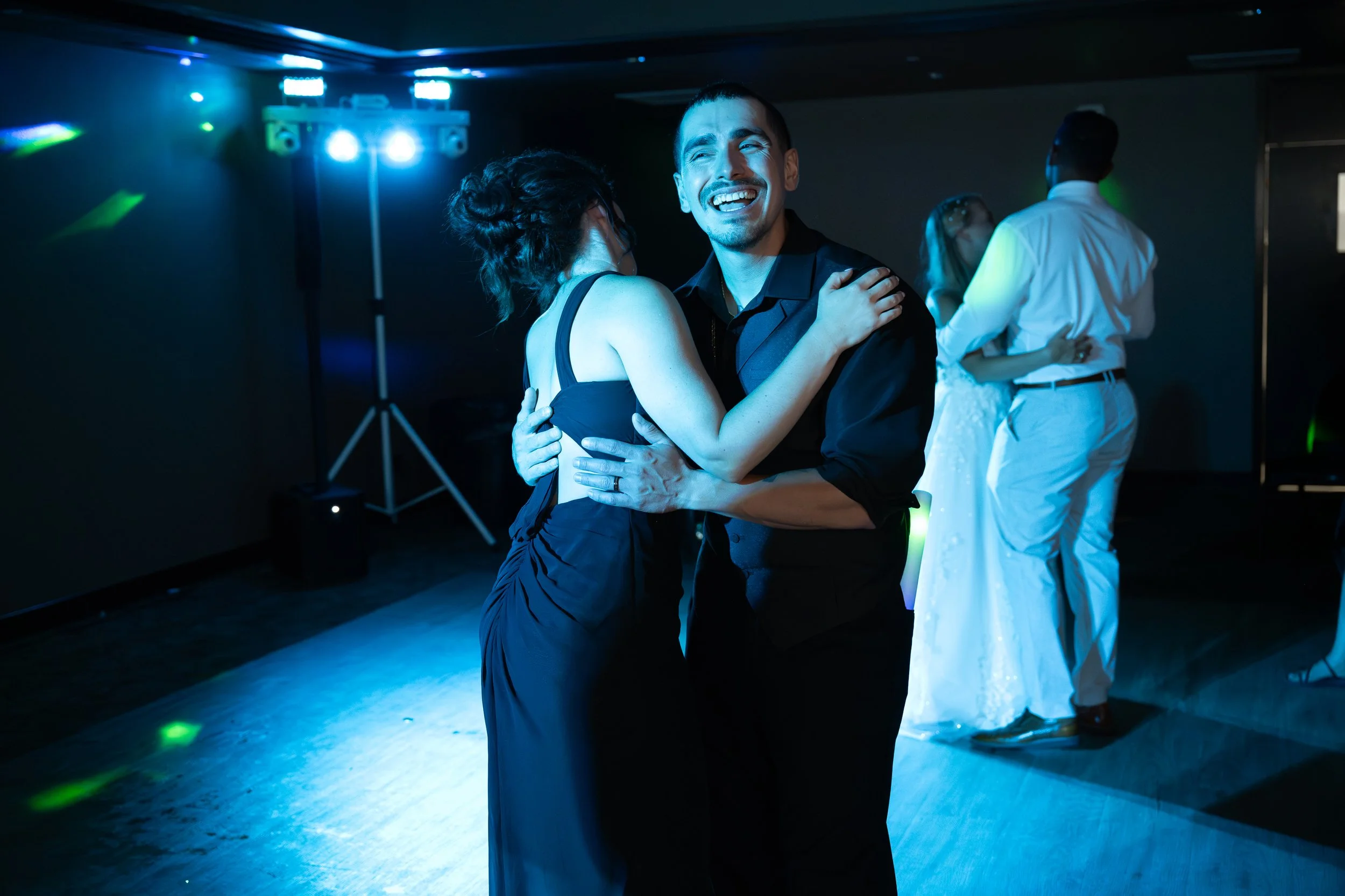 Two couples dancing on a dance floor with ballroom lights