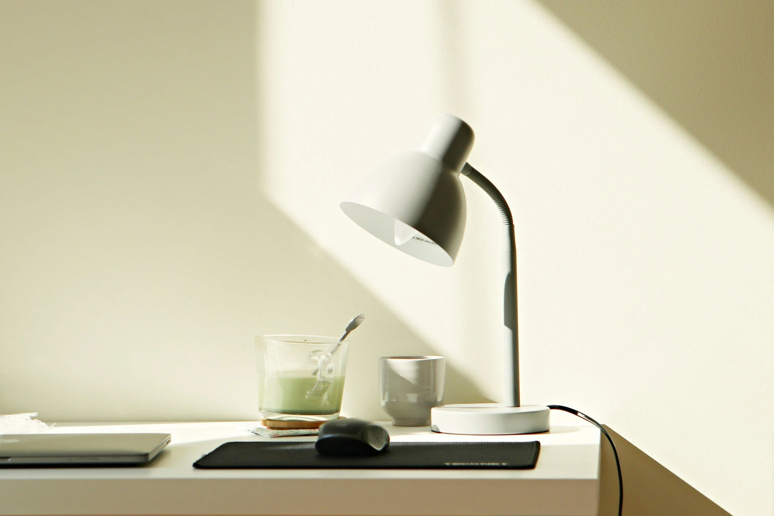 Tidy desk with a lamp, a laptop, and a mug in soft afternoon sunlight