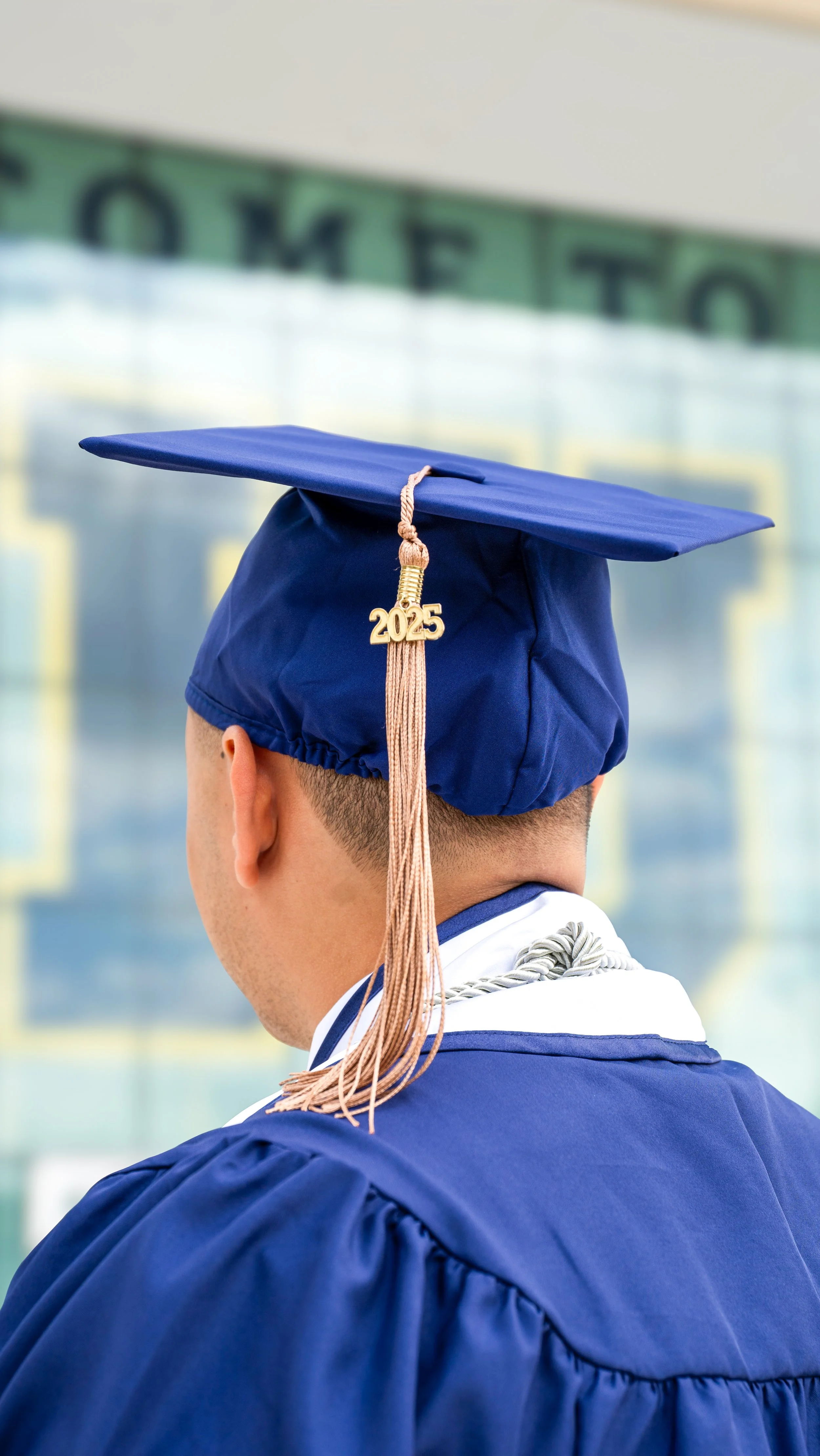 Graduate wearing a blue cap with a "2022" tassel, holding a graduation gown with "FIU" logo.