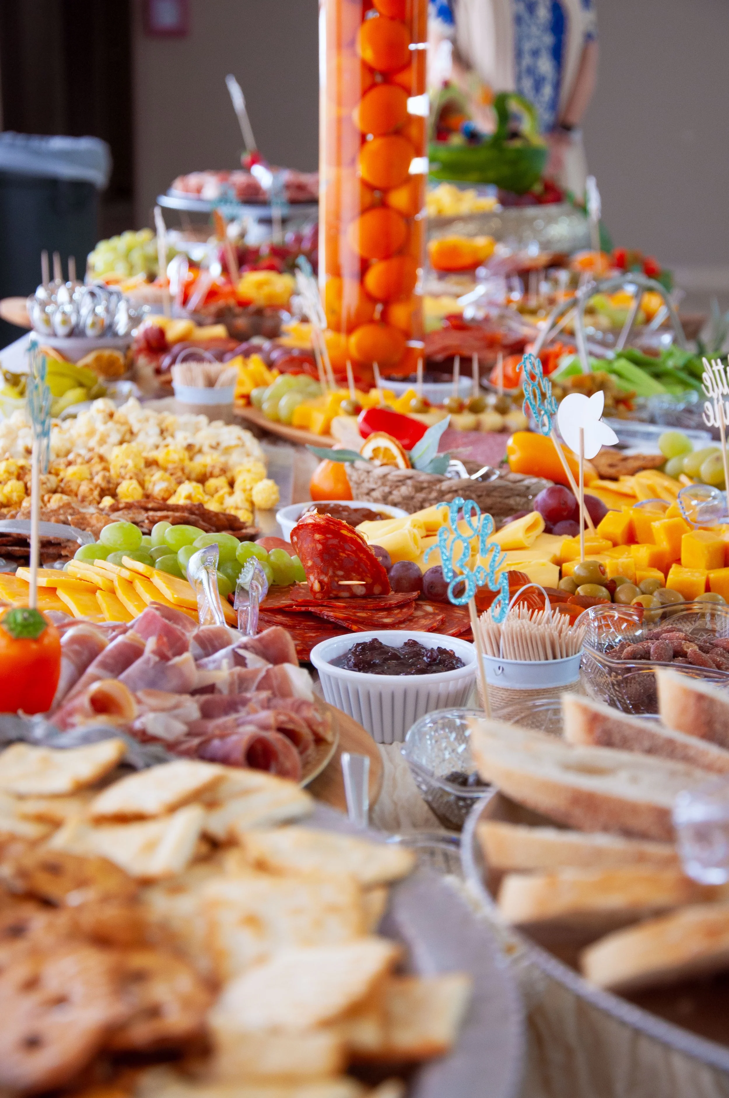 Variety of fresh fruits, sliced meats, cheeses, crackers, and bread on a buffet table.