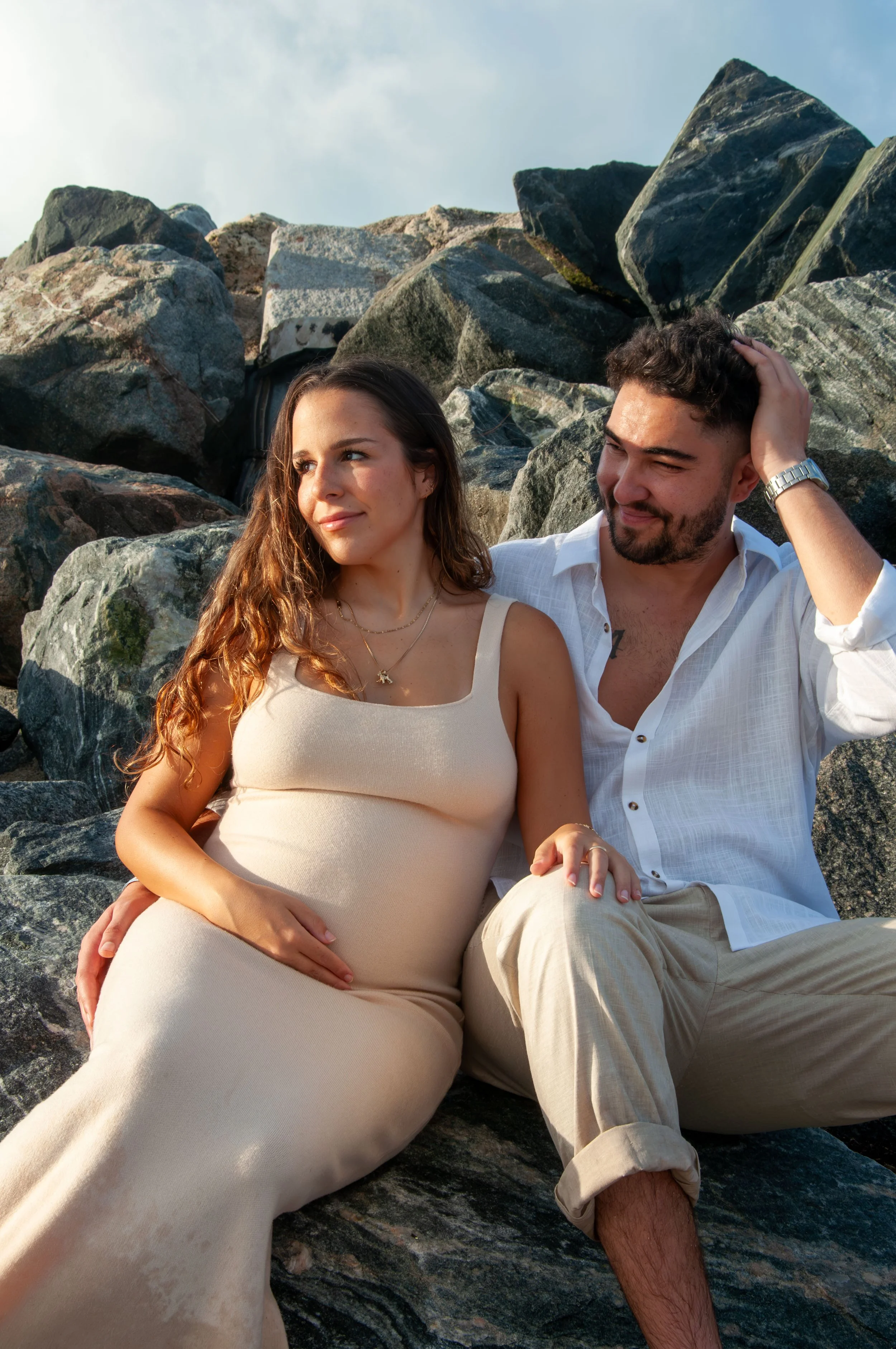 Pregnant woman and man sitting on rocks outdoors