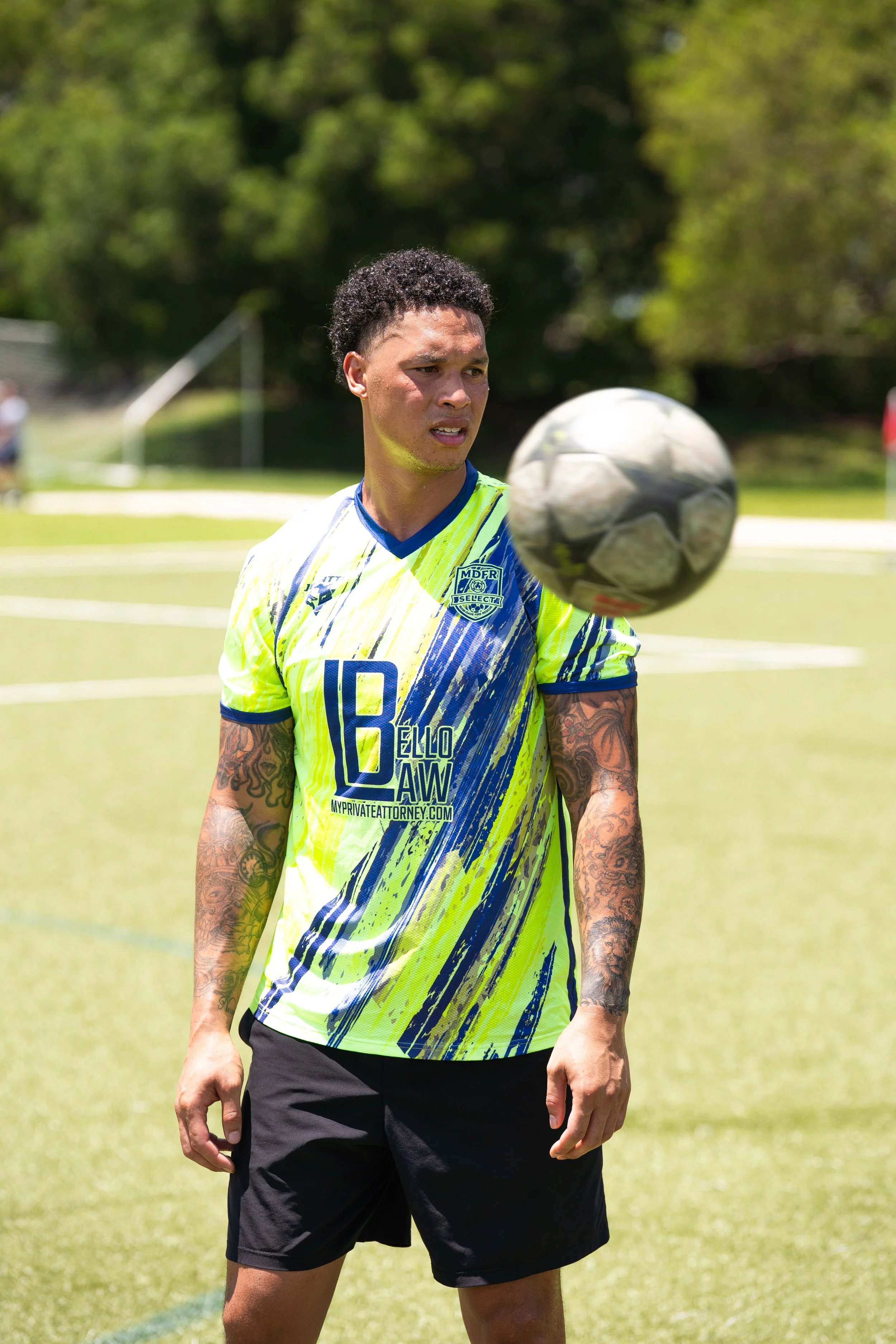 Pregnant woman and partner sitting on rocks by the ocean, holding her belly, with a sign saying 'Baby Dozzo Coming Soon December 2024.'