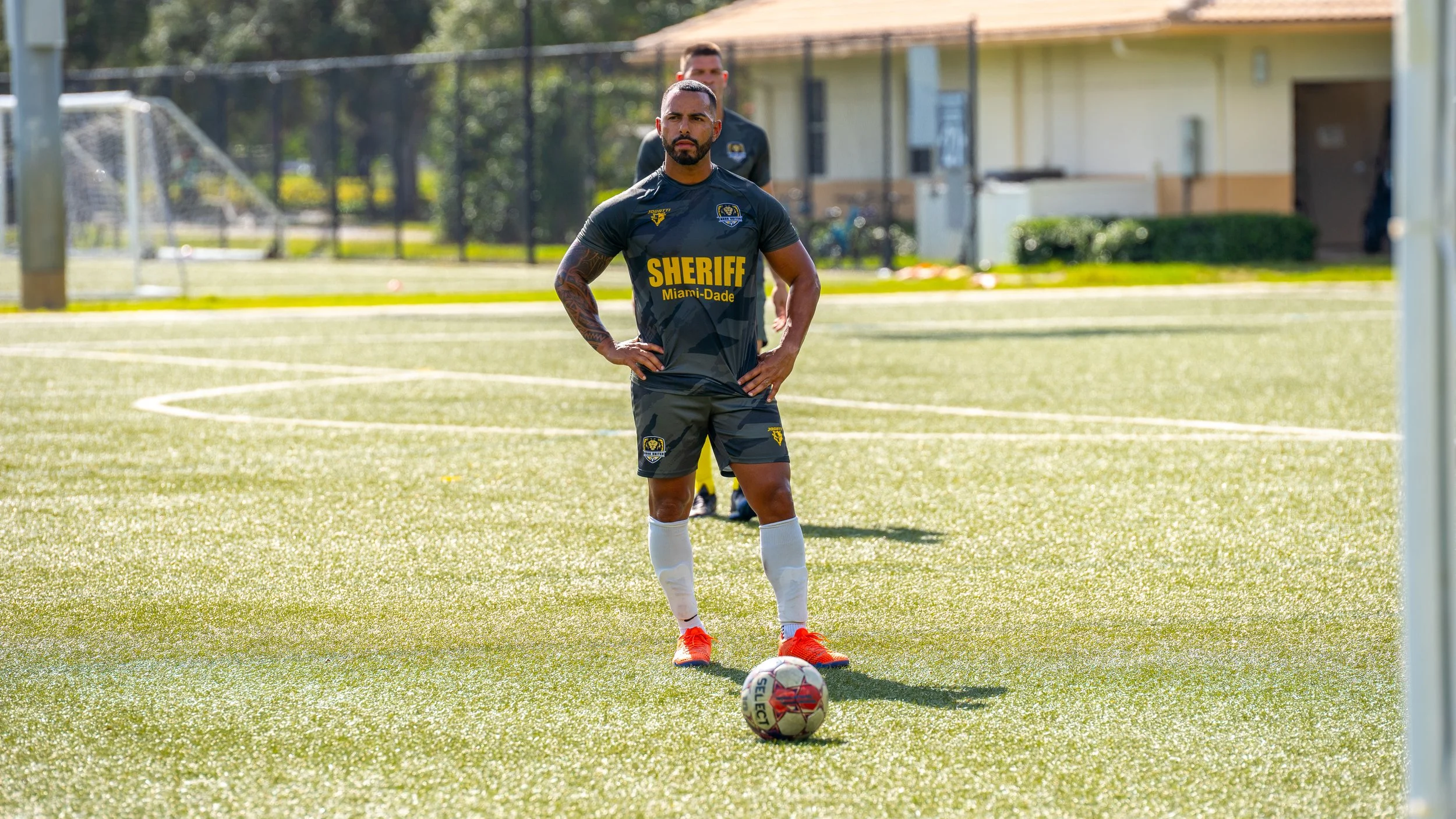 Close-up of a pregnant woman with a man's arms around her, both forming a heart shape over her belly with their hands.