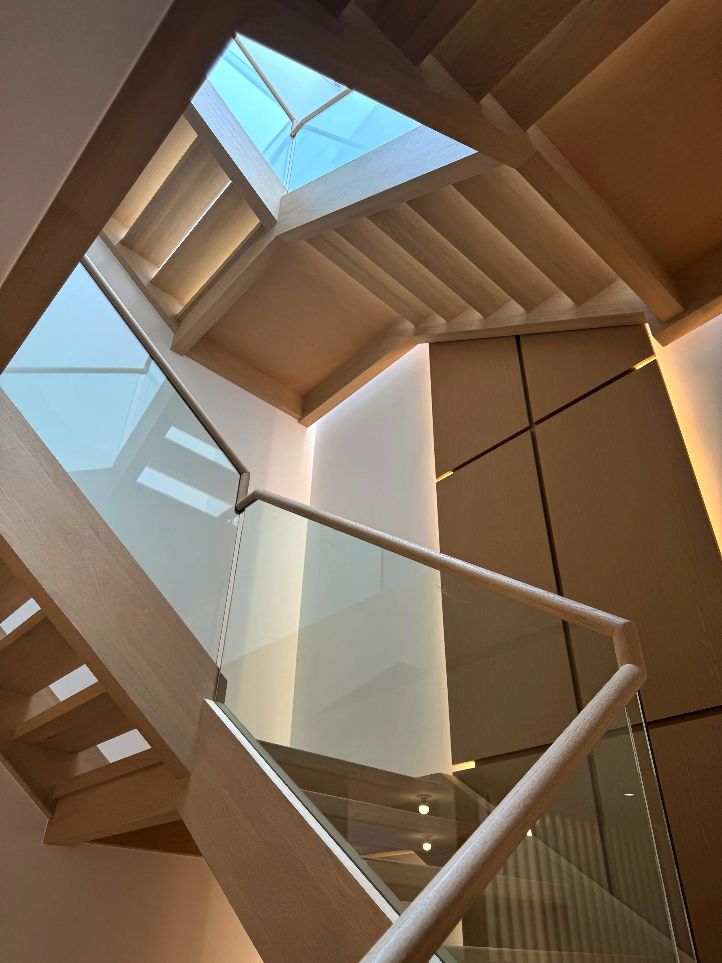 Gallery House by These Architects winding oak staircase against the oak art wall