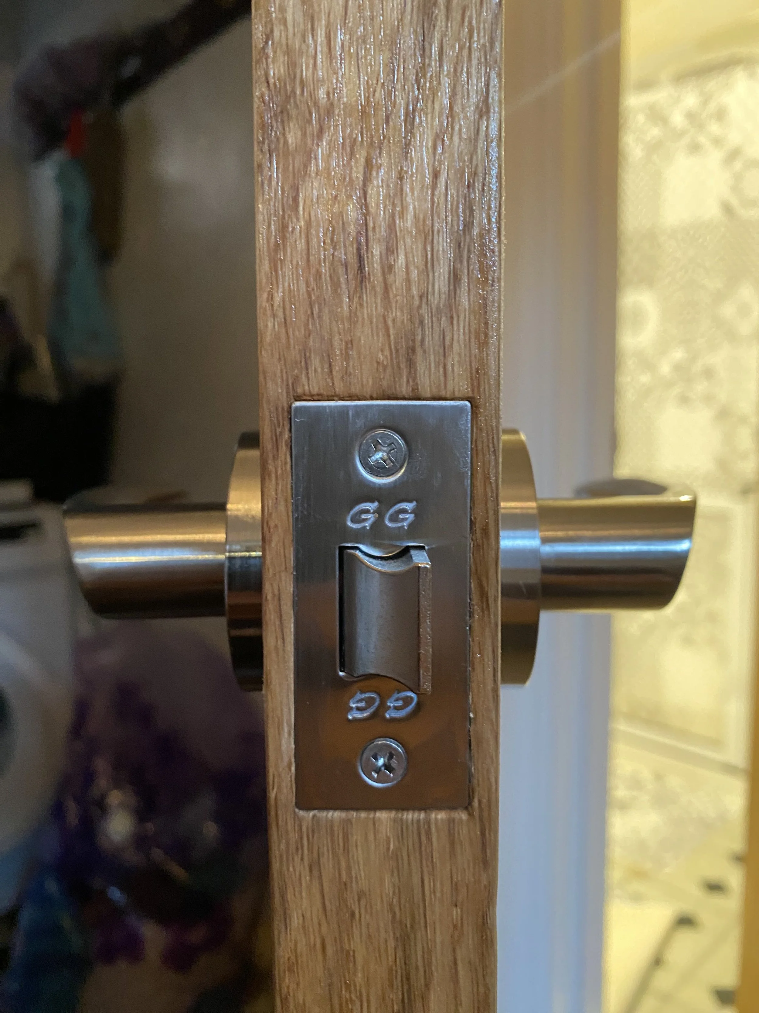 Close-up photograph of a metal latch mechanism installed on a wooden door or frame.