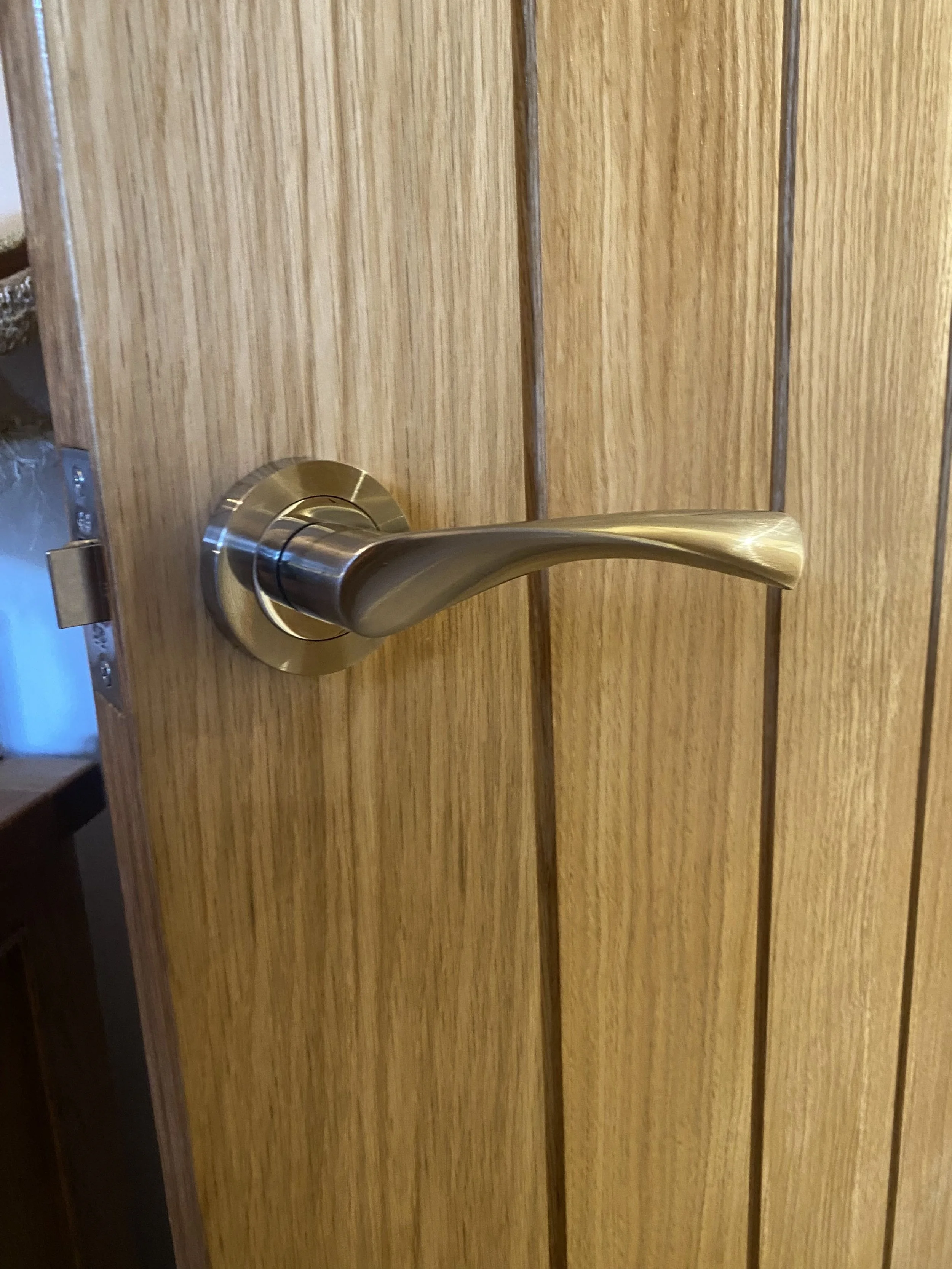 Close-up of a modern, brushed nickel door handle mounted on a wooden door with vertical wood grain paneling.