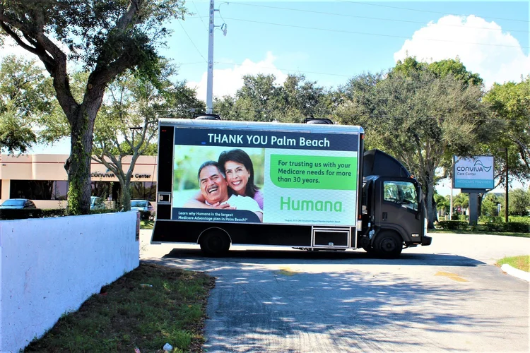 Digital LED billboard truck showing a Humana healthcare ad in Palm Beach