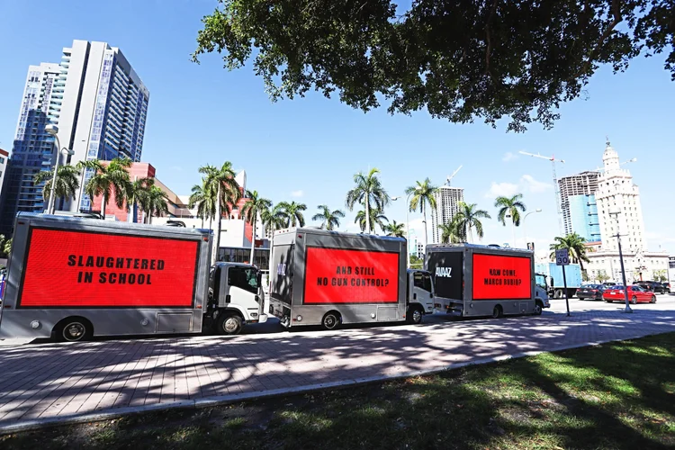 Three digital LED billboard trucks lined up on a city street
