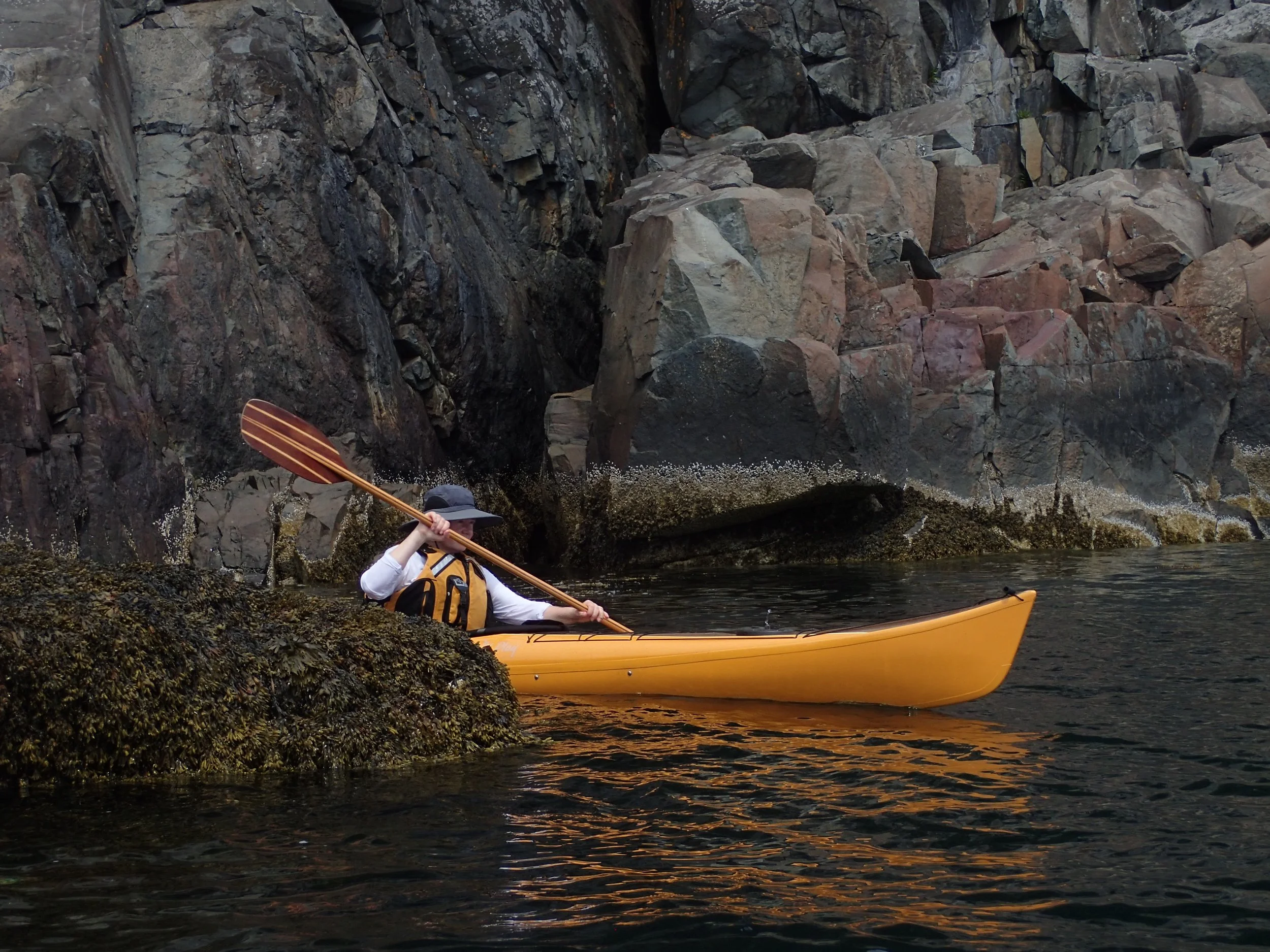 Person kayaking near rocky shoreline