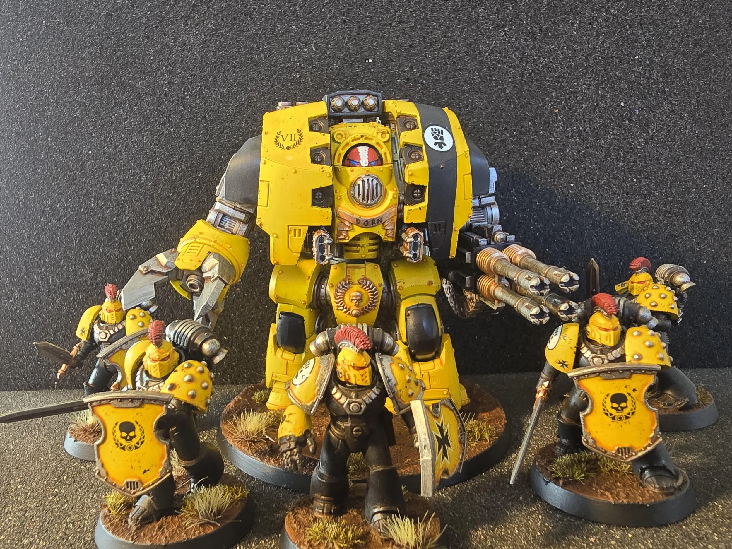 A set of Warhammer Age of Darkness miniatures, including a large yellow Leviathan and six smaller armored space marines, all painted with yellow and black color schemes with skull insignias, posed on round bases with grassy terrain.