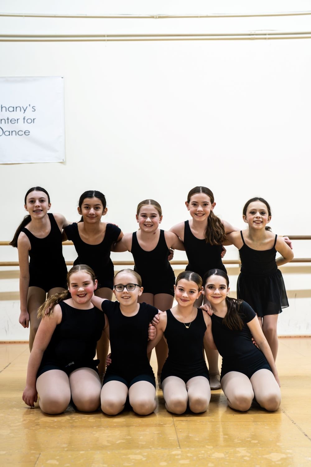 A team of dancers at Bethany's Center for Dance wearing black outfits and smiling.