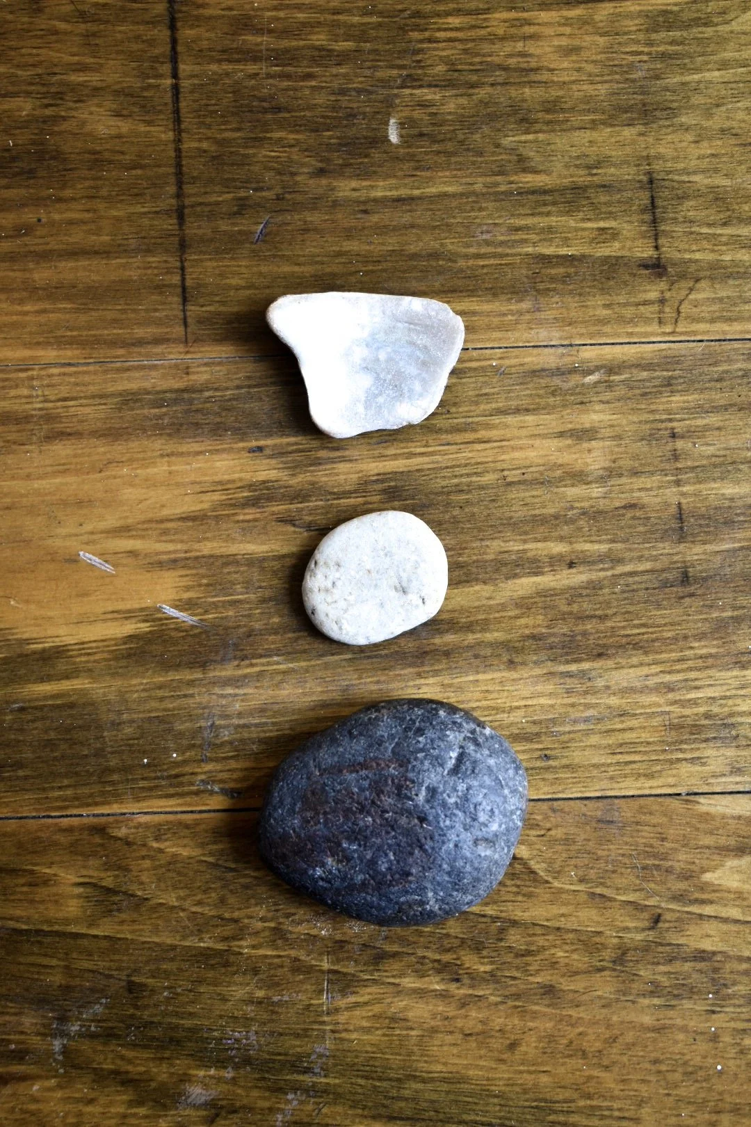 Four stones of different shapes and colors placed on a wooden surface.