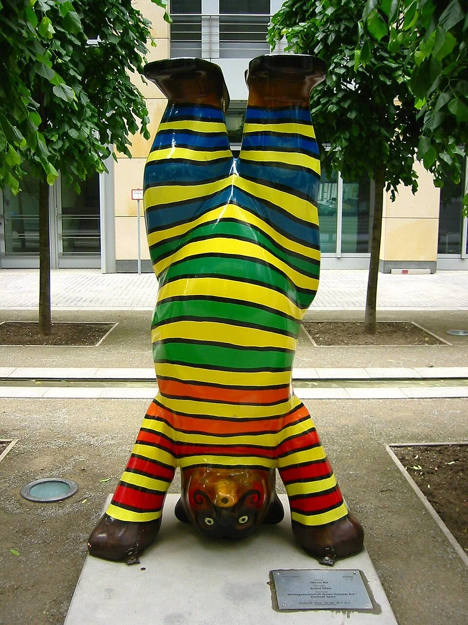 Bear performing handstand in striped bodysuit.